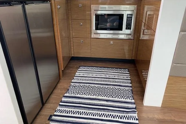 Slide: The Image of Modern kitchen area in a 2018 Cruisers Yachts 45 Cantius with stainless appliances and patterned rug. - 9
