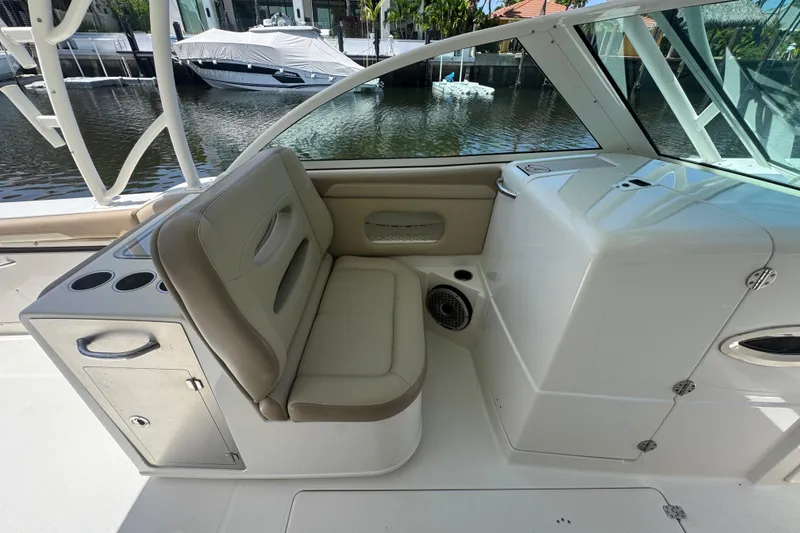 Slide: The Image of 2017 Sailfish 325 DC boat interior with cushioned seating and cup holders by the water. - 14