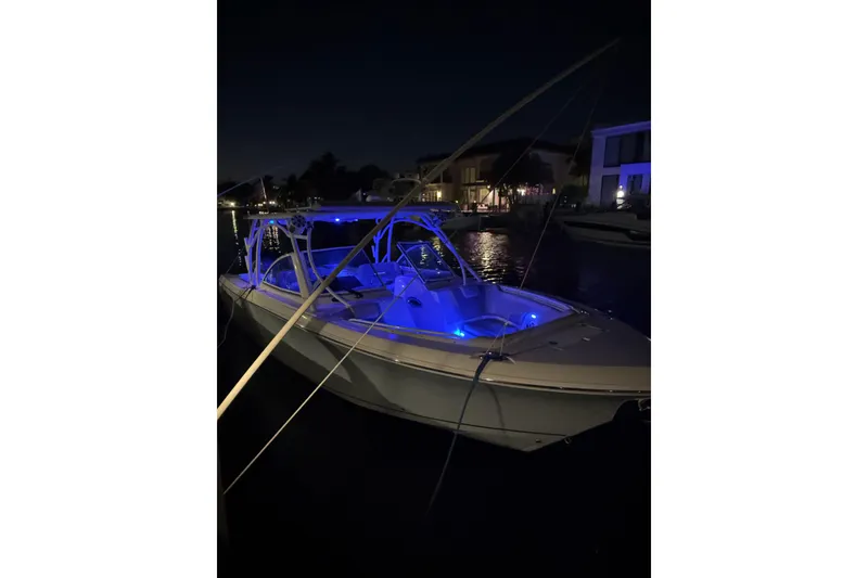 Slide: The Image of 2017 Sailfish 325 DC boat illuminated with blue lights at night. - 18