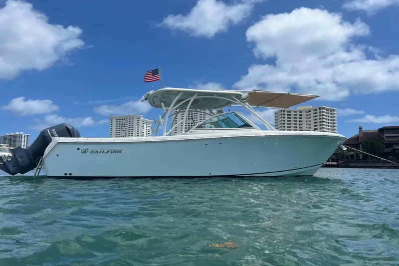 Slide: The Image of 2017 Sailfish 325 DC boat on water, city skyline in background, clear blue sky. - 2