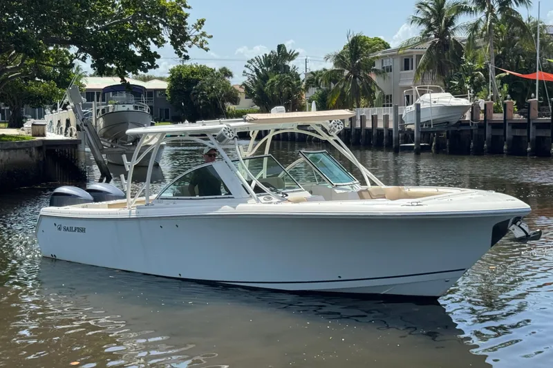 Slide: The Image of 2017 Sailfish 325 DC boat docked on a sunny waterfront with palm trees. - 4