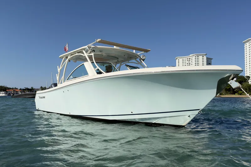 Slide: The Image of 2017 Sailfish 325 DC boat on water, clear sky, modern buildings in background. - 1