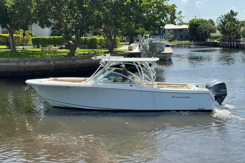 Slide: The Image of 2017 Sailfish 325 DC boat cruising on a calm canal with lush greenery. - 3