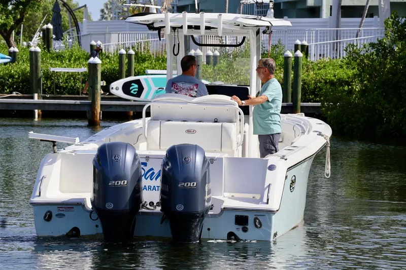 Slide: The Image of 2018 Sea Hunt Gamefish 27 Coffin Box boat with dual Yamaha engines on a calm waterway. - 3