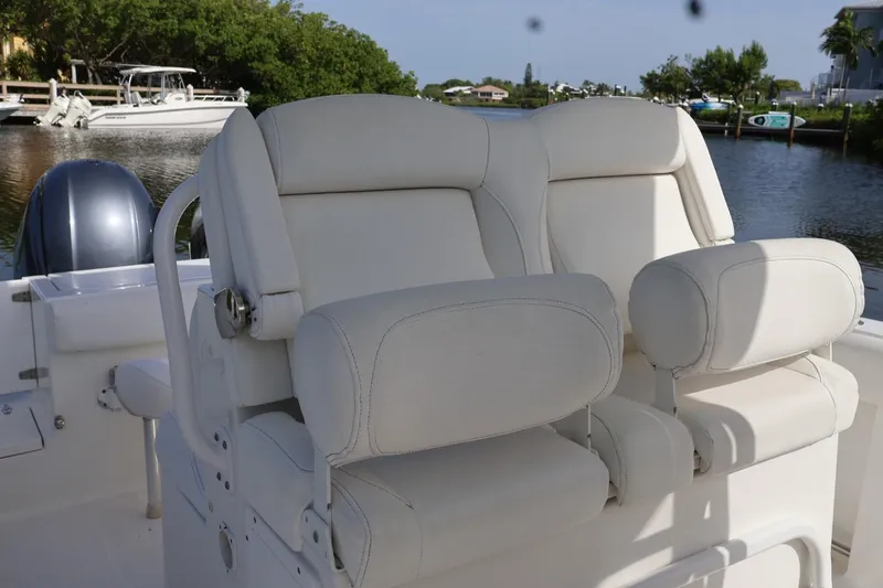 Slide: The Image of 2018 Sea Hunt Gamefish 27 Coffin Box boat with white cushioned seating, docked by a serene waterway. - 12