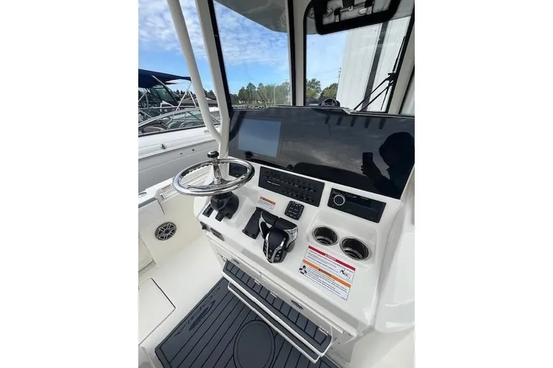 Slide: The Image of 2026 Cobia 245 Center Console boat dashboard with steering wheel and controls. - 3