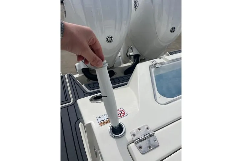 Slide: The Image of Hand adjusting rod holder on 2026 Cobia 245 Center Console boat deck. - 12