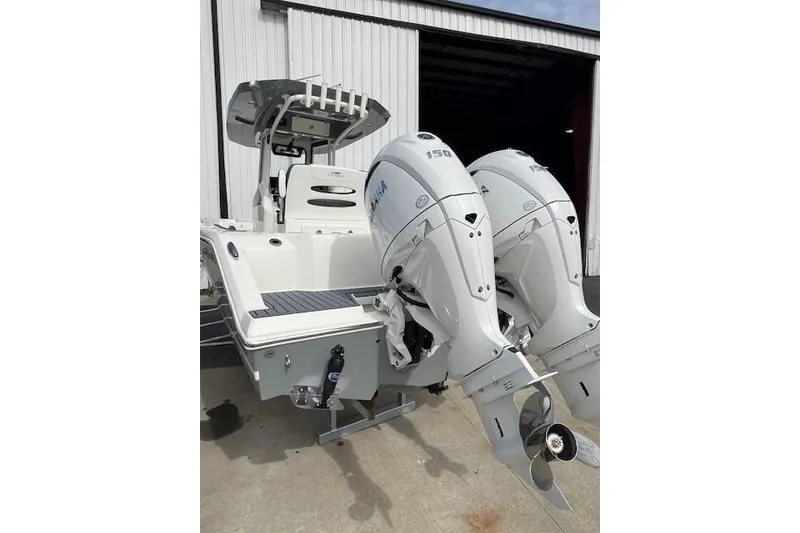 Slide: The Image of 2026 Cobia 245 Center Console boat with dual outboard engines, docked near a warehouse. - 4