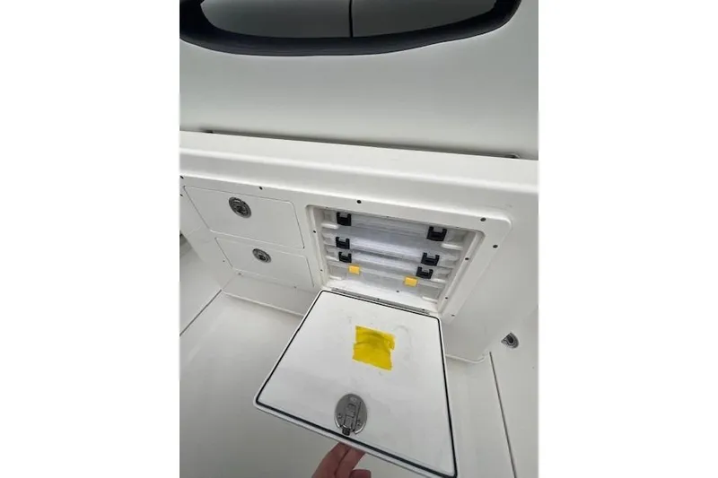 Slide: The Image of 2026 Cobia 245 Center Console storage compartment with open hatch and visible latches. - 16