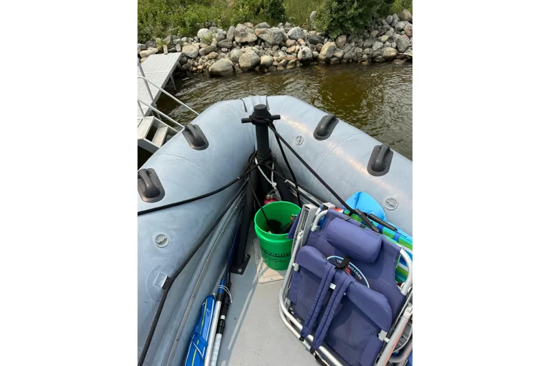 Slide: The Image of Inflatable boat docked by rocky shore, featuring fishing gear and chairs. Willard Marine Sea Force 730, 1996. - 27
