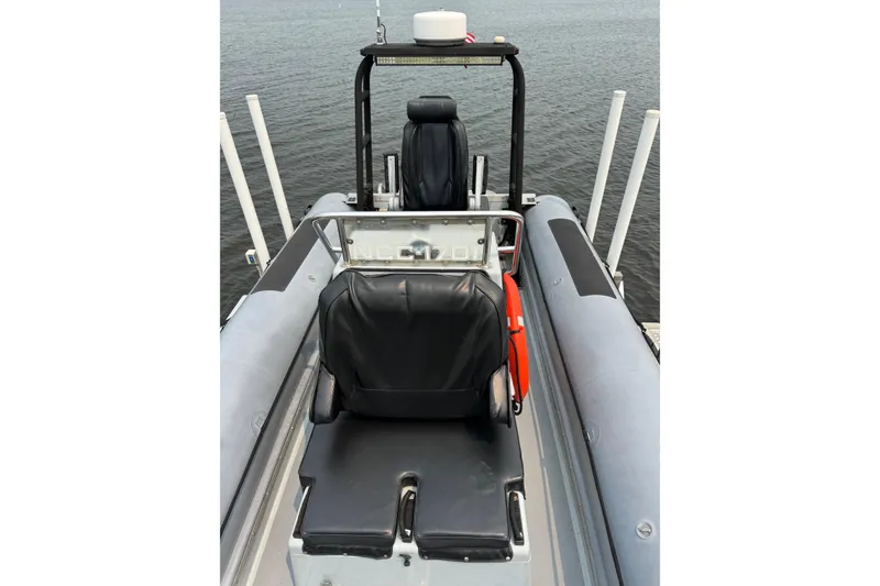 Slide: The Image of 1996 Willard Marine Sea Force 730 boat interior with black seating, docked on calm water. - 29
