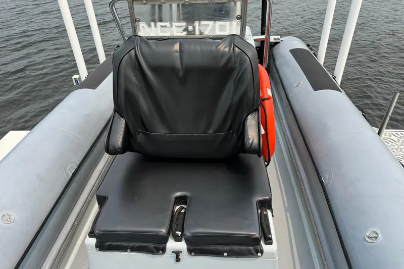 Slide: The Image of Black seat on 1996 Willard Marine Sea Force 730 boat, with life preserver and water backdrop. - 25