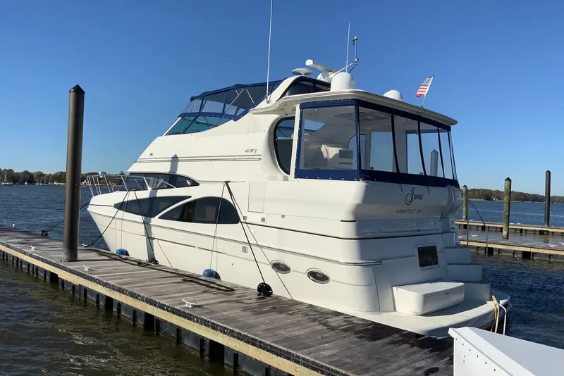Slide: The Image of 2005 Carver 466 Motor Yacht docked on a sunny day, showcasing sleek design and spacious deck. - 2