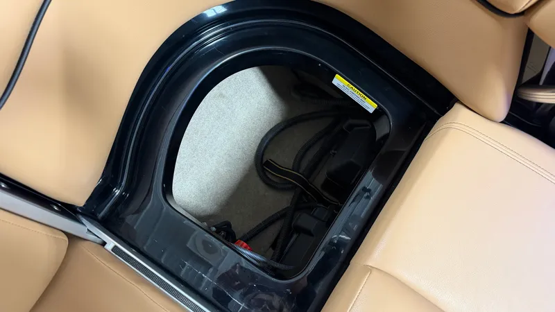 Slide: The Image of An open storage compartment inside a boat with beige upholstery and black edges. - 36