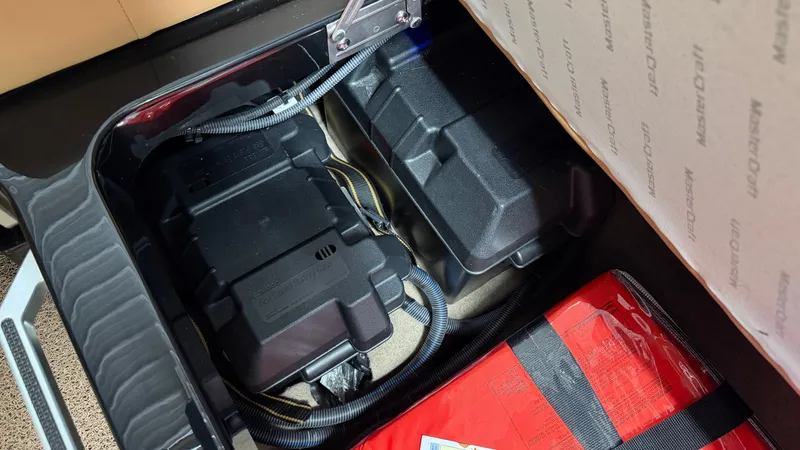 Slide: The Image of View of a 2019 MasterCraft XT22 storage area with batteries and a red item. - 45