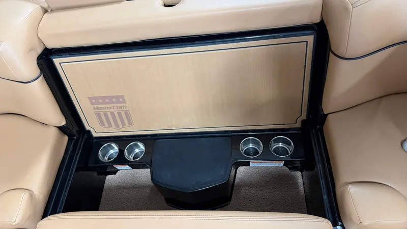 Slide: The Image of The rear seat of a 2019 MasterCraft XT22 with cup holders and a wood panel. - 33