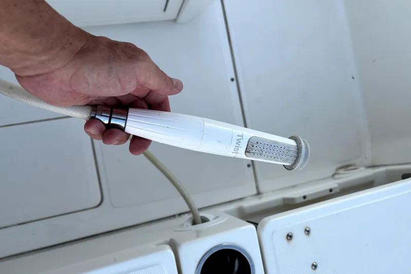 Slide: The Image of Hand holding a hose nozzle on a 2022 Boston Whaler 250 Dauntless boat deck. - 38