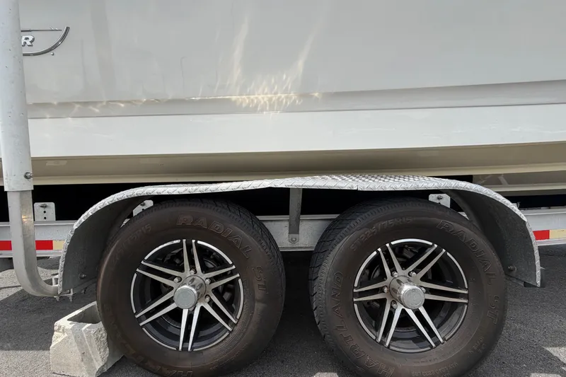Slide: The Image of Trailer wheels of a 2022 Boston Whaler 250 Dauntless boat on pavement. - 66