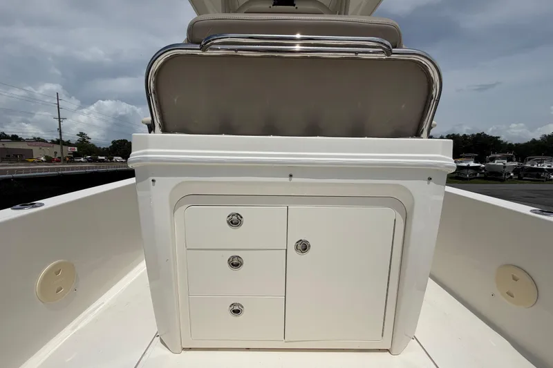 Slide: The Image of 2022 Boston Whaler 250 Dauntless boat console with storage compartments under a cloudy sky. - 14