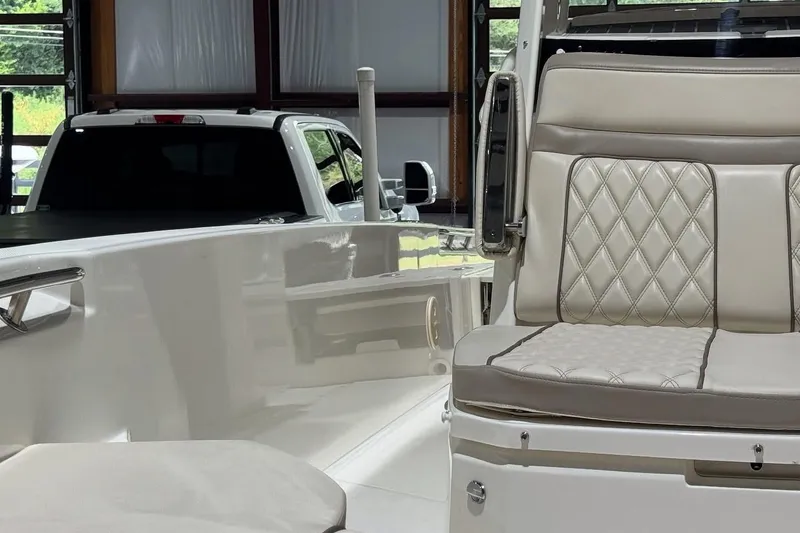 Slide: The Image of 2022 Boston Whaler 250 Dauntless boat interior with quilted seating, parked near a white truck. - 13