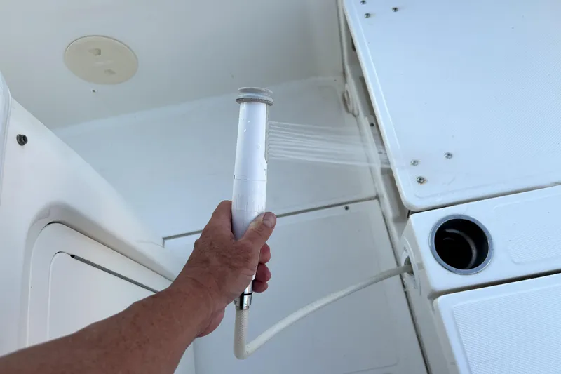 Slide: The Image of Hand holding a shower hose on a 2022 Boston Whaler 250 Dauntless boat deck. - 31
