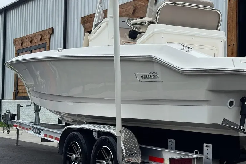 Slide: The Image of 2022 Boston Whaler 250 Dauntless boat on trailer, parked near a building. - 4