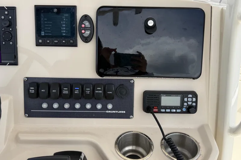 Slide: The Image of Control panel of a 2022 Boston Whaler 250 Dauntless boat with switches and radio. - 24