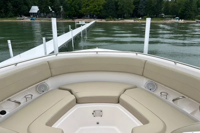 Slide: The Image of 2018 Pursuit DC 325 Dual Console boat with beige seating, docked by a serene lake. - 14