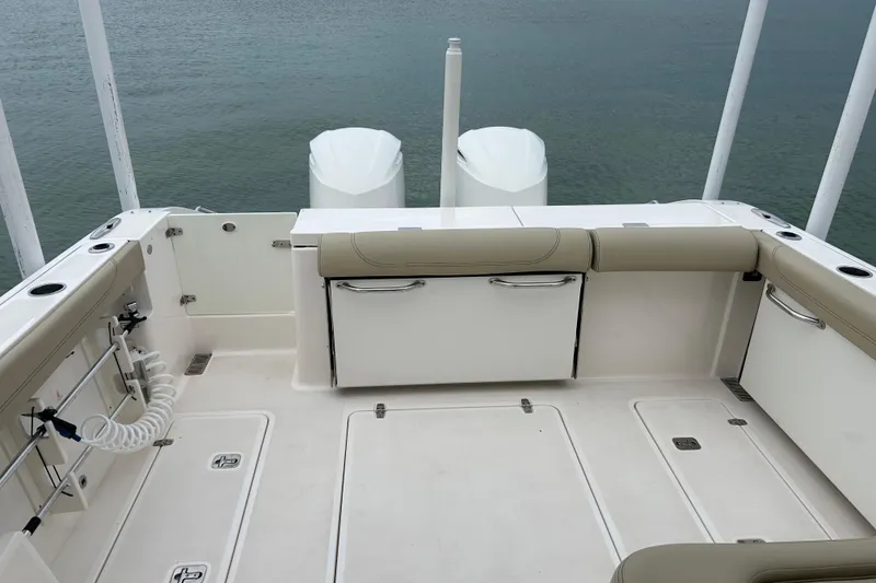 Slide: The Image of 2018 Pursuit DC 325 Dual Console boat deck with seating and storage, overlooking calm water. - 4