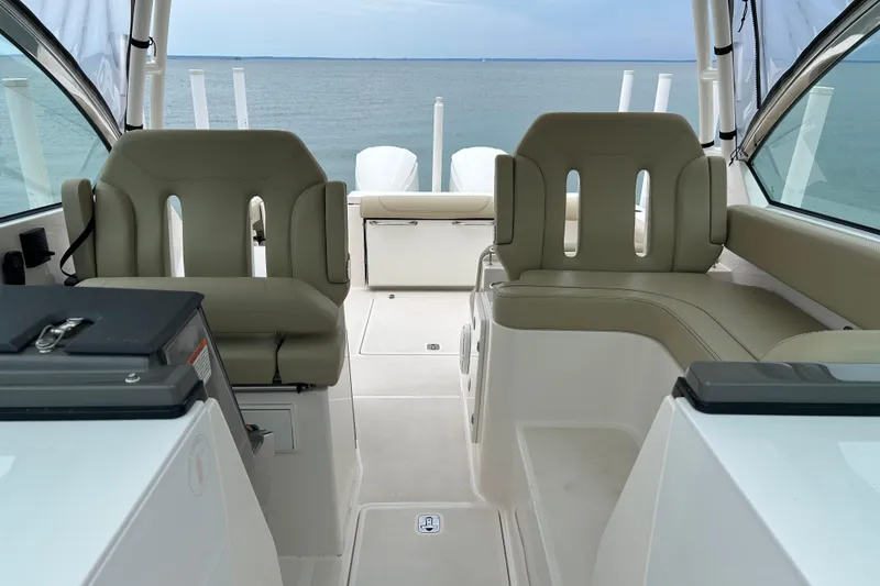 Slide: The Image of 2018 Pursuit DC 325 Dual Console boat interior with beige seating and ocean view. - 9
