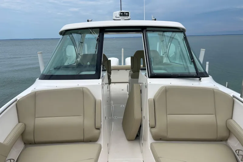Slide: The Image of 2018 Pursuit DC 325 Dual Console boat interior with beige seating, ocean view. - 13