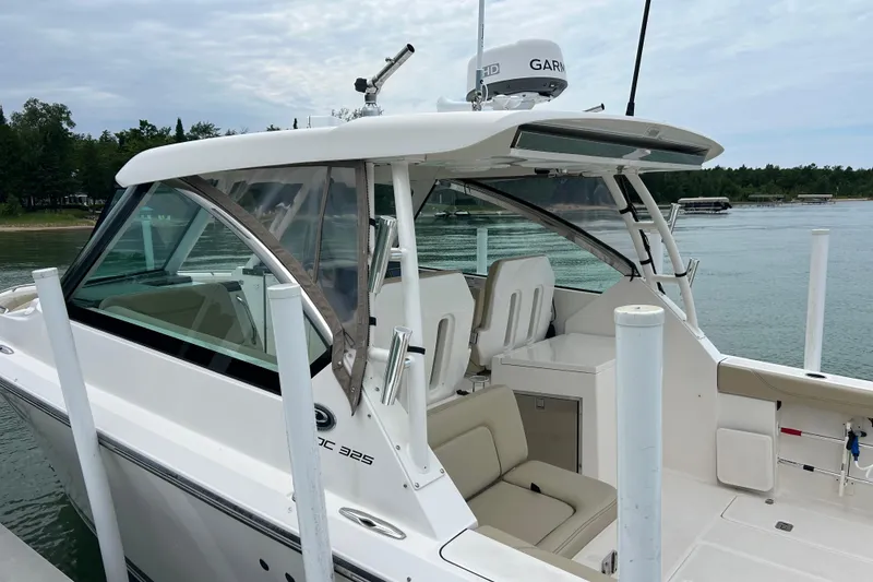 Slide: The Image of 2018 Pursuit DC 325 Dual Console boat docked by the water, featuring sleek design and seating. - 1