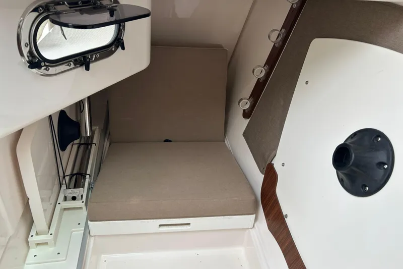 Slide: The Image of 2018 Pursuit DC 325 Dual Console cabin interior with cushioned seating and porthole window. - 16