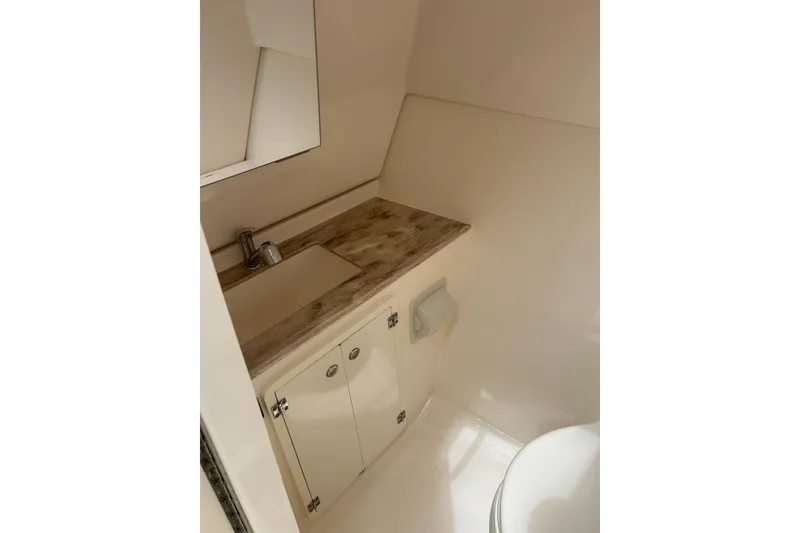 Slide: The Image of 2018 Pursuit DC 325 Dual Console boat bathroom with sink, mirror, and storage cabinet. - 18