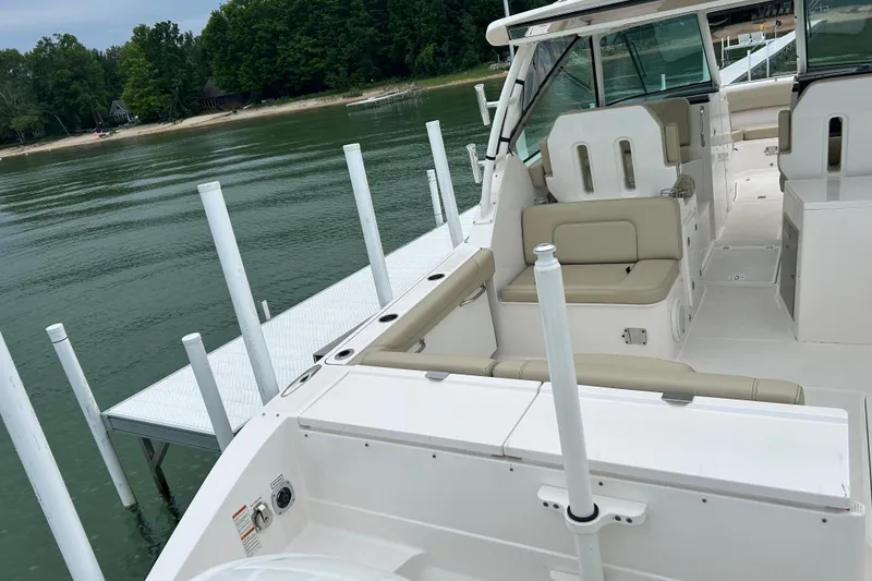 Slide: The Image of 2018 Pursuit DC 325 Dual Console boat docked by a serene lakeside. - 2