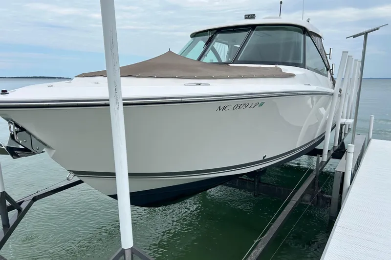 Slide: The Image of 2018 Pursuit DC 325 Dual Console boat on lift, docked by the water. - 19