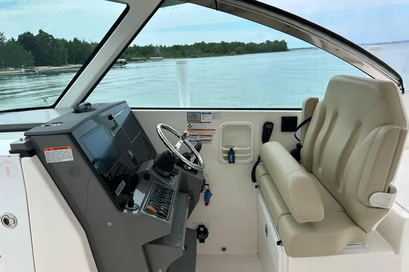Slide: The Image of 2018 Pursuit DC 325 Dual Console helm with beige seating, steering wheel, and control panel. - 11