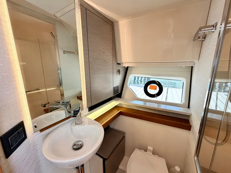 Slide: The Image of The image shows the bathroom of a 2022 Tiara Yachts 43 LE. It features a sink, toilet, and a window with an outdoor view. - 43