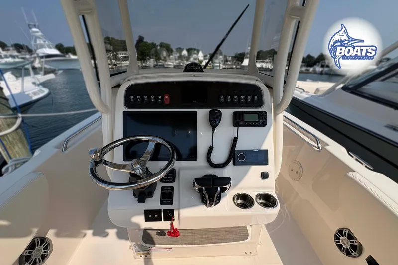 Slide: The Image of 2024 Grady-White Fisherman 257 helm with steering wheel and control panel at marina. - 8