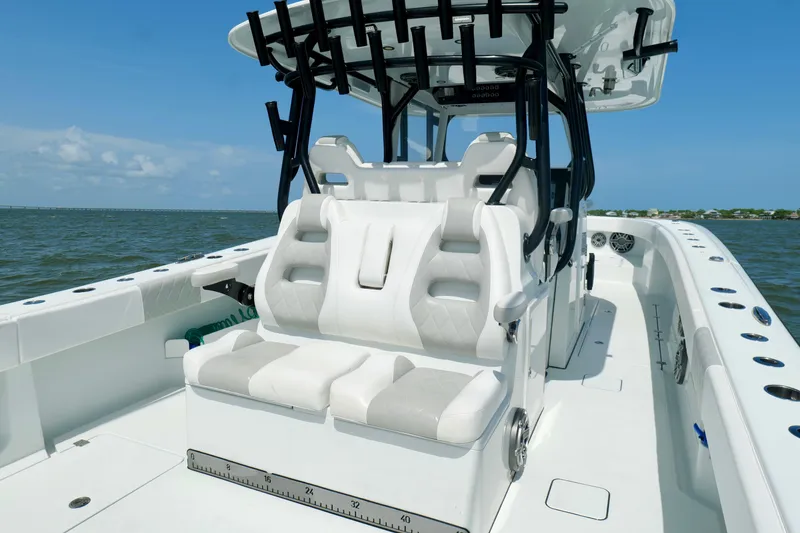 Slide: The Image of 2024 Freeman 38 boat interior with white seating and rod holders on a sunny day. - 27