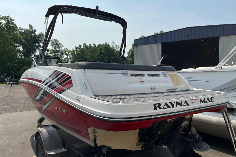 Slide: The Image of 2022 Bayliner VR5 Bowrider I/O boat with custom graphics, parked near a warehouse. - 3