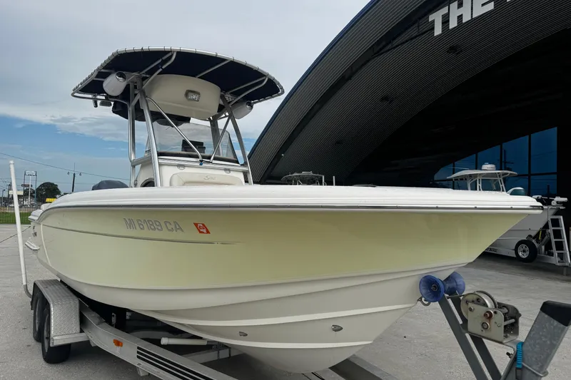 Slide: The Image of 2006 Scout 222 Sportfish boat on trailer, parked outside a modern building. - 9