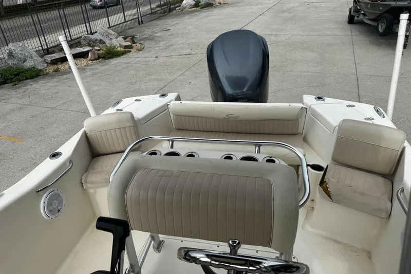 Slide: The Image of 2006 Scout 222 Sportfish boat interior with seating and motor, parked on concrete. - 12