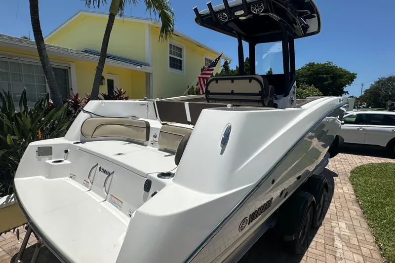 Slide: The Image of 2024 Yamaha Boats 255 FSH Sport H docked near a yellow house, showcasing sleek design. - 2