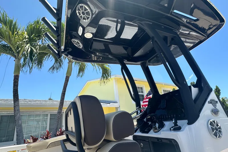 Slide: The Image of 2024 Yamaha Boats 255 FSH Sport H interior with T-top and console, palm trees in background. - 3