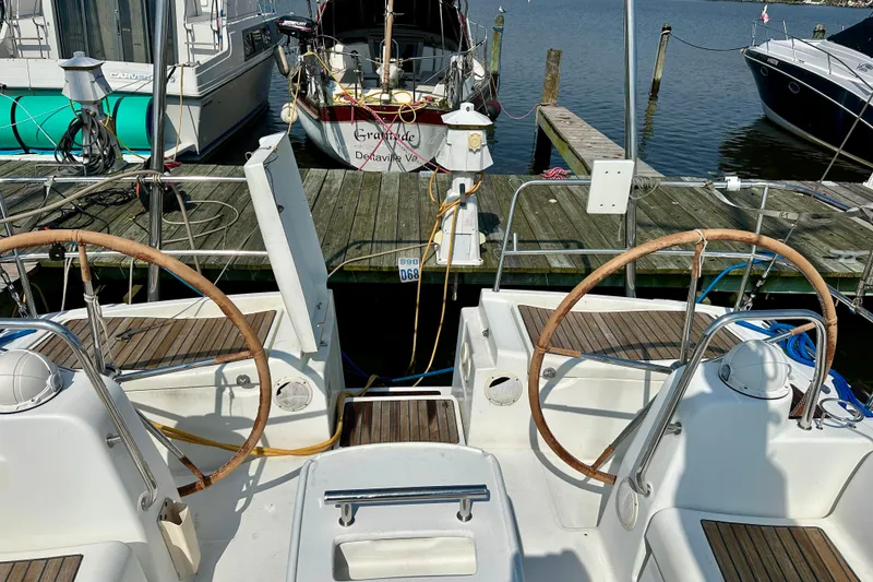 Slide: The Image of 2010 Beneteau Oceanis 40 sailboat docked, featuring dual steering wheels and wooden deck. - 17