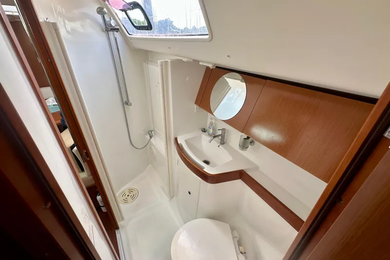 Slide: The Image of Bathroom interior of 2010 Beneteau Oceanis 40 yacht, featuring shower, sink, and wooden cabinetry. - 51
