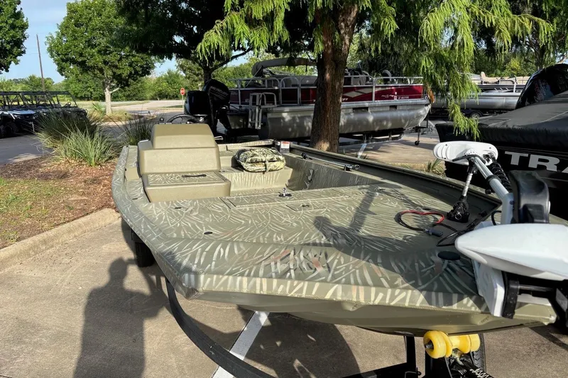 Slide: The Image of 2014 Tracker Grizzly 1754 SC boat parked outdoors under trees. - 7
