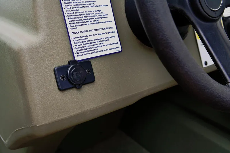 Slide: The Image of Close-up of a 2024 Tracker Grizzly 1754 SC helm with steering wheel and power outlet. - 18