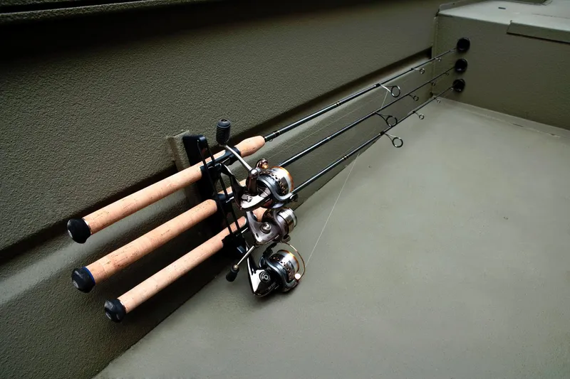 Slide: The Image of Three fishing rods with cork handles are neatly secured in a holder on the side of a boat. - 19